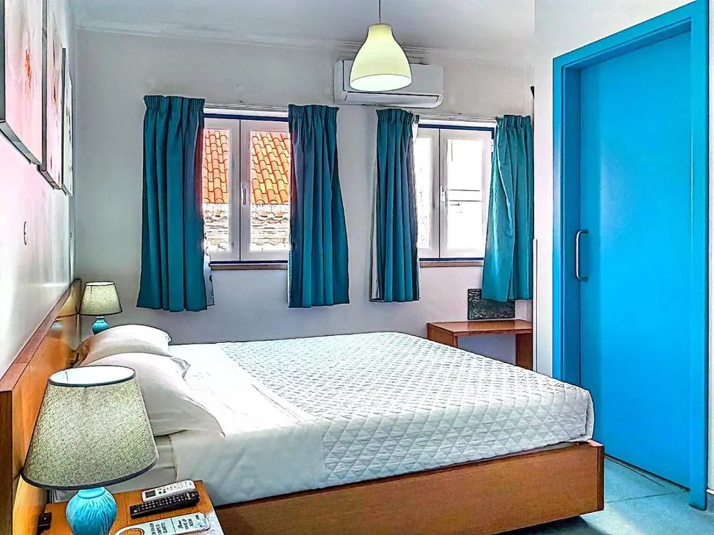 A bright WEAA Hotel room with turquoise curtains and a comfortable double bed